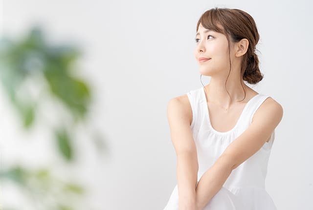 白いワンピースを着て微笑みながら横を見る女性